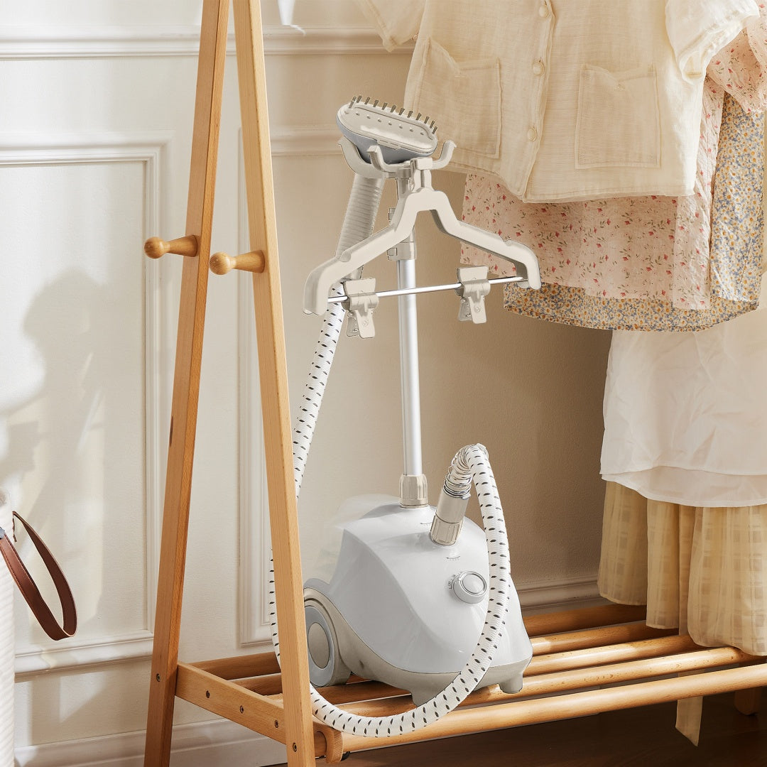 White garment steamer on a wooden stand with clothes in the background