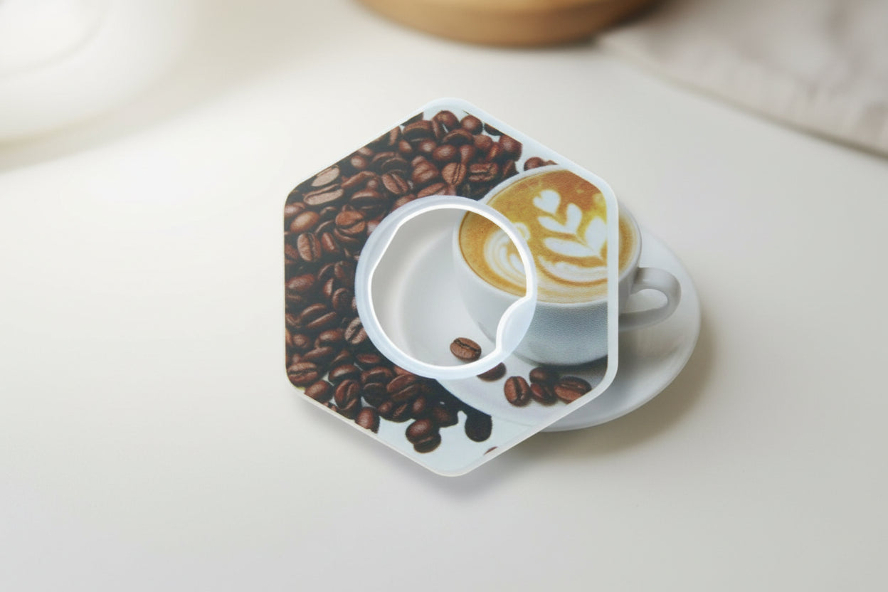 Hexagonal coaster with coffee design featuring coffee beans and a cappuccino on a white surface.