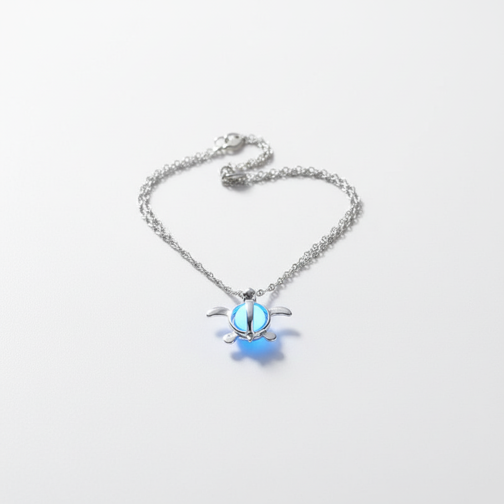 Silver turtle-shaped pendant with blue glow on a white background